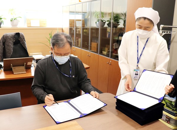 3월 15일 가톨릭대학교 서울성모병원 이요섭 영성부원장이 김연순 사회사업팀장과 함께 사회공헌 활동을 위한 총 31개 사회복지기관과의 협약서에 사인을 하고 있다.