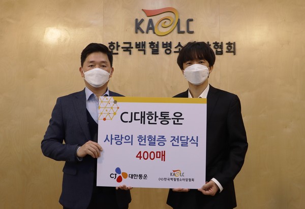 CJ대한통운 박진규 부장(왼쪽)이 한국백혈병소아암협회 서용화 과장(오른쪽)에게 헌혈증을 전달하고 기념촬영하고 있다.