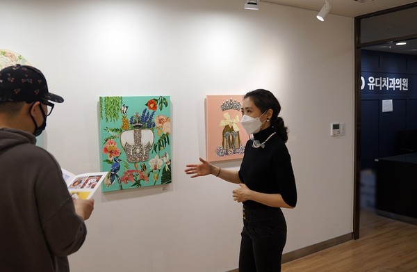 문민정 작가(오른쪽)가 유디갤러리를 찾은 환자에게 작품을 소개하는 모습