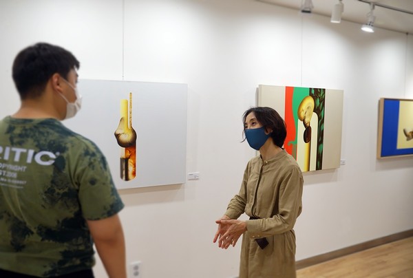 강윤정 작가(오른쪽)가 유디갤러리를 찾은 관람객에게 작품을 설명하고 있다.